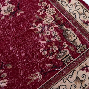 May include: A vintage red rug with a floral pattern and a beige border. The rug features a central field of deep red with faded floral motifs in beige and brown. The border has an intricate design with floral and geometric elements.