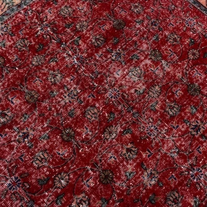 K&ouml;nnte beinhalten: Nahaufnahme eines roten Vintage-Teppichs mit einem komplizierten Blumenmuster. Der Teppich hat einen Used-Look mit verblassten Farben und einem detaillierten Rand. Das Design umfasst verschiedene florale und geometrische Elemente.