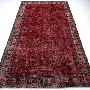 K&ouml;nnte beinhalten: Ein rechteckiger, verwaschen roter Teppich mit detailliertem Blumenmuster. Der Teppich hat einen dunklen Rand mit einem helleren rosa Innenrand. Das Mittelfeld ist tiefrot mit einem sich wiederholenden Blumendesign. Geeignet f&uuml;r Wohn- und Schlafzimmer.