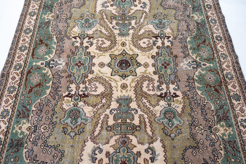 May include: A rectangular area rug featuring a complex central medallion and intricate floral motifs in shades of sage green, dusty rose, cream, and deep maroon. The border displays a repeating geometric pattern with stylized botanical elements.