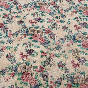 Pode incluir: Um tapete vintage com fundo bege e padr&atilde;o floral. O tapete apresenta flores rosa, azuis e roxas com folhas verdes. A borda &eacute; de cor bord&ocirc; escuro. Este tapete &eacute; adequado para salas de estar e quartos.