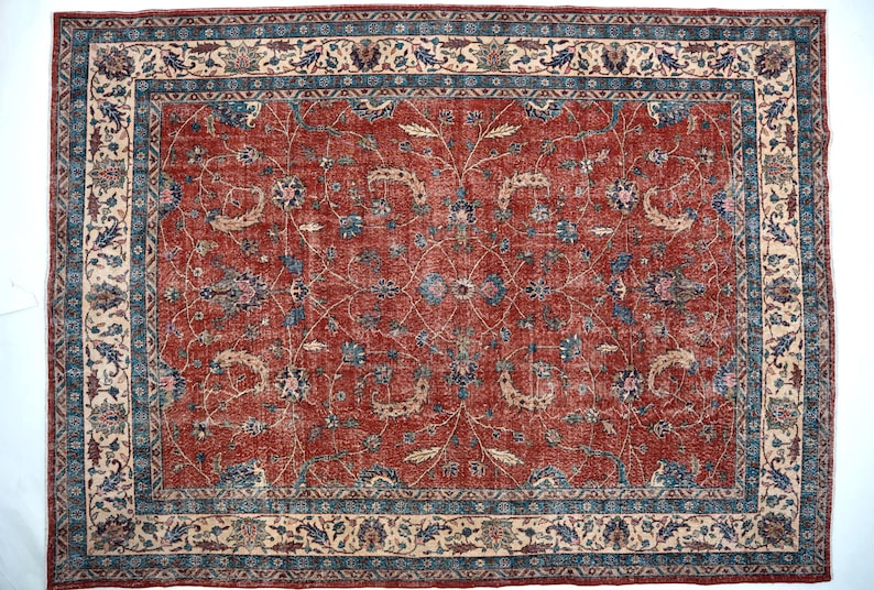 May include: Rectangular red rug with an intricate floral pattern. The rug features a central field of red with a detailed design of blue and beige floral motifs. A border of blue and beige floral patterns frames the rug.