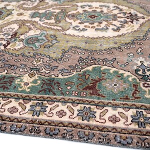 May include: A woven area rug featuring a complex pattern of paisley and floral motifs in shades of sage green, dusty rose, cream, and slate blue. The design includes a central medallion and a detailed border with repeating geometric flower shapes.
