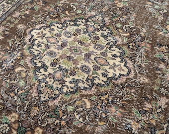 May include: Brown and beige vintage rug with an intricate floral pattern. The rug features a central medallion design with a cream background and colorful floral accents. The border is a darker brown with floral motifs.