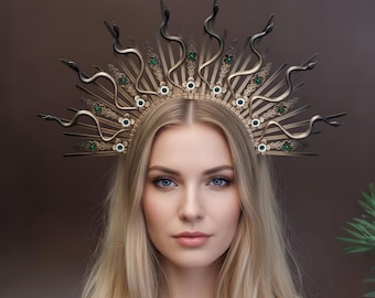 Puede incluir: Una corona dorada con un diseño de sol, con detalles serpentinos y gemas verde esmeralda. La corona la lleva una persona con pelo largo rubio y ojos azules. La estética general es regia y elegante.