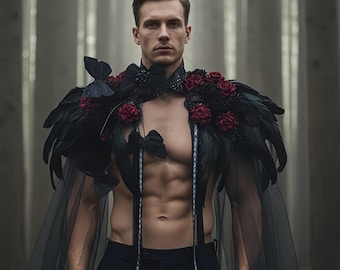 Puede incluir: Una capa negra con una pieza de hombro con plumas adornada con rosas rojas y mariposas negras. La persona está en un bosque con árboles altos y un fondo brumoso. La capa está hecha de una tela negra transparente.