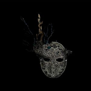 May include: Ornate silver masquerade mask with intricate lace-like detailing and embellishments. The mask features a decorative crown of branches and a dark background, creating a dramatic effect. Perfect for a masquerade ball or costume party.