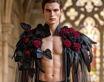 Puede incluir: Una pieza decorativa para los hombros con plumas negras, mariposas de tela oscura y rosas de color rojo intenso y negro. La prenda incluye largos paneles de tela negra transparente que caen, creando un efecto de capas sobre el torso.