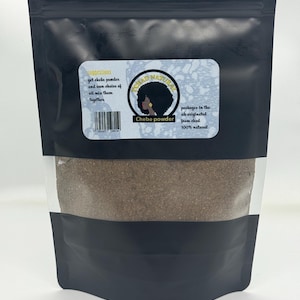 May include: A black pouch of Chebe powder with a clear window, showing the brown powder. The label reads "CHAD NATURAL" and "Chebe powder", with instructions to mix with oil. The product is packaged in the UK and is 100% natural.