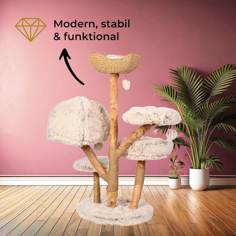 Puede incluir: Un &aacute;rbol para gatos de varios niveles con acabado de madera natural, con m&uacute;ltiples plataformas de felpa y una cama estilo cesta tejida. El &aacute;rbol incluye un juguete colgante y est&aacute; sobre un fondo rosa con el texto "Modern, stabil & funktional".