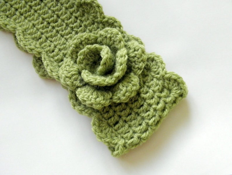 May include: A green crocheted headband with a large flower detail.