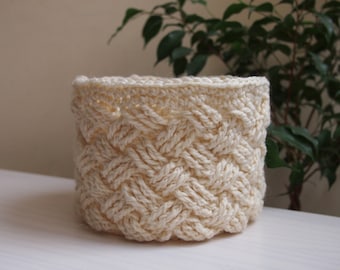 May include: A crocheted basket with a woven pattern in a cream color.