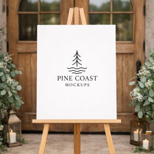 May include: A white sign on a wooden easel with the text "PINE COAST MOCKUPS" and a tree logo. The sign is in front of a wooden door and greenery. Two lanterns with candles are on either side of the easel.