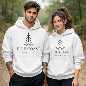 May include: Two people wearing white hooded sweatshirts. Each sweatshirt features a black tree and wave graphic, with the text "PINE COAST MOCKUPS". The hoodies have a front pocket and drawstring hood.