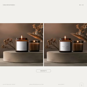 May include: Two amber glass candle jars with labels. One jar has a white label with the text "smoke + earth" and the other jar has a blank white label. Both jars are lit and sitting on a gray concrete platform with dried flowers and tall grass behind them.