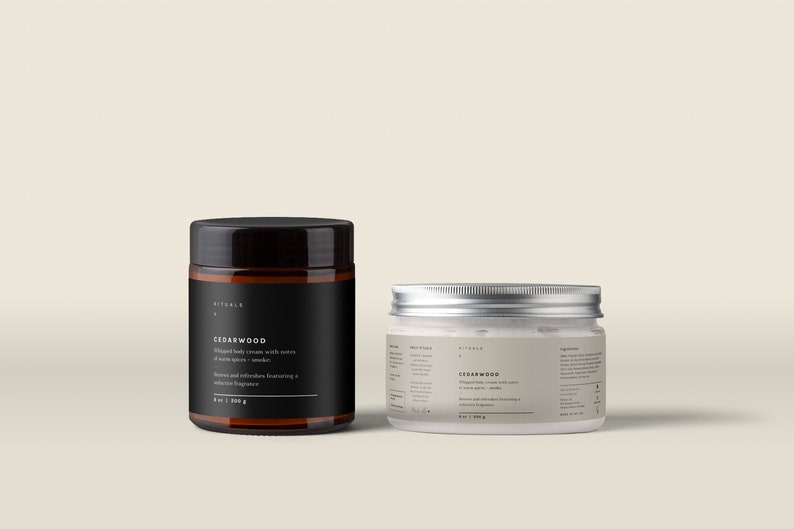 May include: Two jars of body cream with the text "Cedarwood" on the labels. One jar is black with a dark wooden lid, the other is clear with a silver lid. The labels include details about the cream's ingredients and fragrance.