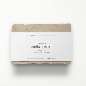 May include: A white bar of soap with a label that reads "Rituals. smoke + earth SOAP BAR JOJOBA + TANTUM 8 oz / 250 g 100% Vegan".