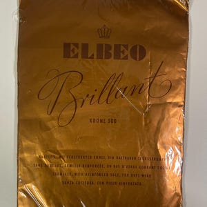 Può includere: Confezione sigillata con finitura metallica dorata. La confezione presenta il marchio "ELBEO" sopra la parola "Brillant" in elegante corsivo. È visibile anche il testo "KRONE 500", insieme a testo in più lingue.