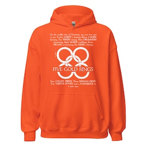 May include: Orange hoodie with a white graphic featuring the text "FIVE GOLD RINGS" and lyrics from the Christmas carol "The Twelve Days of Christmas". The hoodie has a hood and a front pocket.