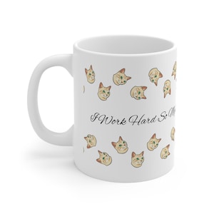 Könnte beinhalten: Weiße Keramiktasse mit Henkel, verziert mit einem sich wiederholenden Muster aus beigefarbenen und grünen Katzenköpfen. Der Becher hat den Text "I Work Hard So My" in schwarzer Schrift.