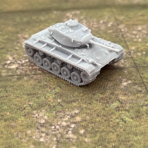 May include: A small, gray model tank with a detailed design, including a turret, cannon, and visible treads. The miniature tank is set against a green and brown textured background, suggesting a battlefield or terrain.