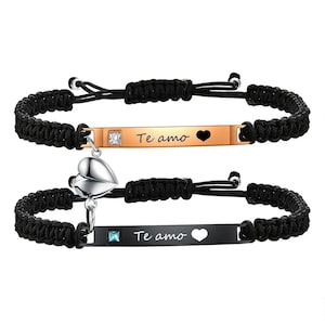 May include: Two matching black braided bracelets. One bracelet has a gold-colored bar with the text "Te amo" and a heart cutout. The other bracelet has a black bar with the same text and a heart cutout. Both bracelets have a heart-shaped charm.