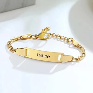 Peut inclure: Un bracelet doré avec un motif de chaîne gourmette. Le bracelet comporte une plaque rectangulaire gravée du mot "name". Le bracelet est réglable et possède une fermeture à mousqueton.