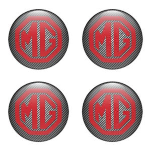 Op de afbeelding: Vier ronde emblemen met de rode letters "MG" in een rood achthoekig kader. De achtergrond heeft een koolstofvezeltextuur. De emblemen zijn glanzend en lijken op stickers of badges.