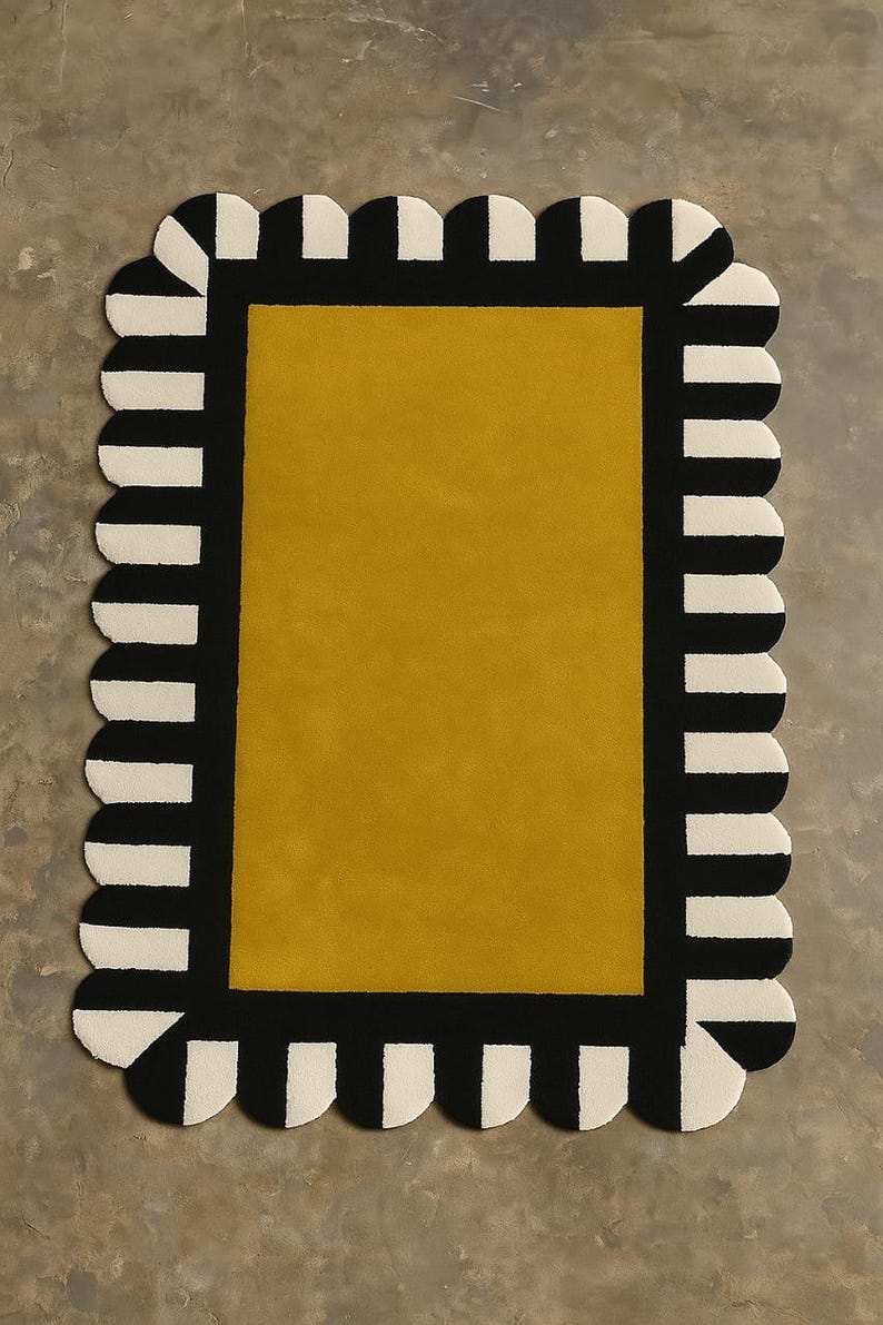 May include: A rectangular rug featuring a solid mustard yellow center panel surrounded by a thick black border. The outer edge of the rug is finished with a scalloped trim that alternates between black and off-white vertical stripes.