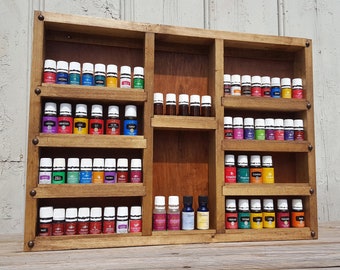 May include: A wooden shelf unit with multiple shelves for storing essential oil bottles. The shelves are stained a dark brown color and have a rustic look. The bottles are arranged in rows and are mostly clear glass with white caps. Some of the bottles have colored liquids inside.