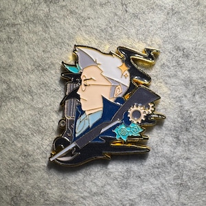 May include: A detailed enamel pin featuring a profile of a person with glasses, white hair, and a blue coat. The pin has gold accents and includes gears, a pen, and floral elements. The design is set against a textured background.