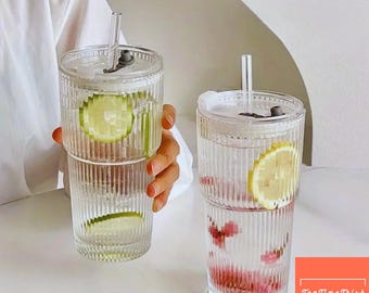 Vaso de vidrio con pajita y tapa, diseño acanalado, ideal para café helado.