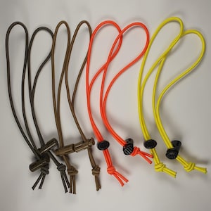 以下が含まれることがあります： さまざまな色の6つの調節可能なストラップのコレクション。ストラップは、濃い茶色、茶色、オレンジ色、黄色です。各ストラップには、黒いプラスチック製のアジャスターと結び目のある端が付いています。