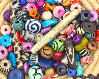 May include: A woven basket filled with colorful beads in various shapes and sizes, including round, cylindrical, and oval beads. The beads are made of wood, bone, and plastic.