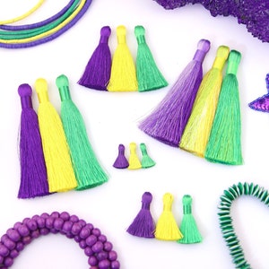 Puede incluir: Surtido de flecos de adorno de varios tamaños en morado, amarillo y verde. Los flecos están hechos de un tejido suave y sedoso y son perfectos para añadir un toque de color y textura a cualquier proyecto.