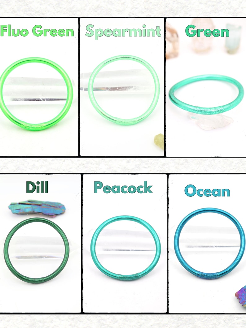 May include: Six colorful bangles in shades of green and blue, including Fluo Green, Spearmint, Green, Dill, Peacock, and Ocean. Each bangle is a solid, circular shape. The names of the colors are written above each bangle.