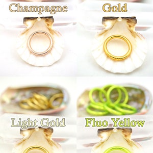 May include: Four seashells with different colored rings inside. The rings are in the colors champagne, gold, light gold, and fluo yellow.