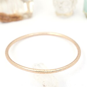 May include: A simple gold-toned bangle bracelet with a textured finish.