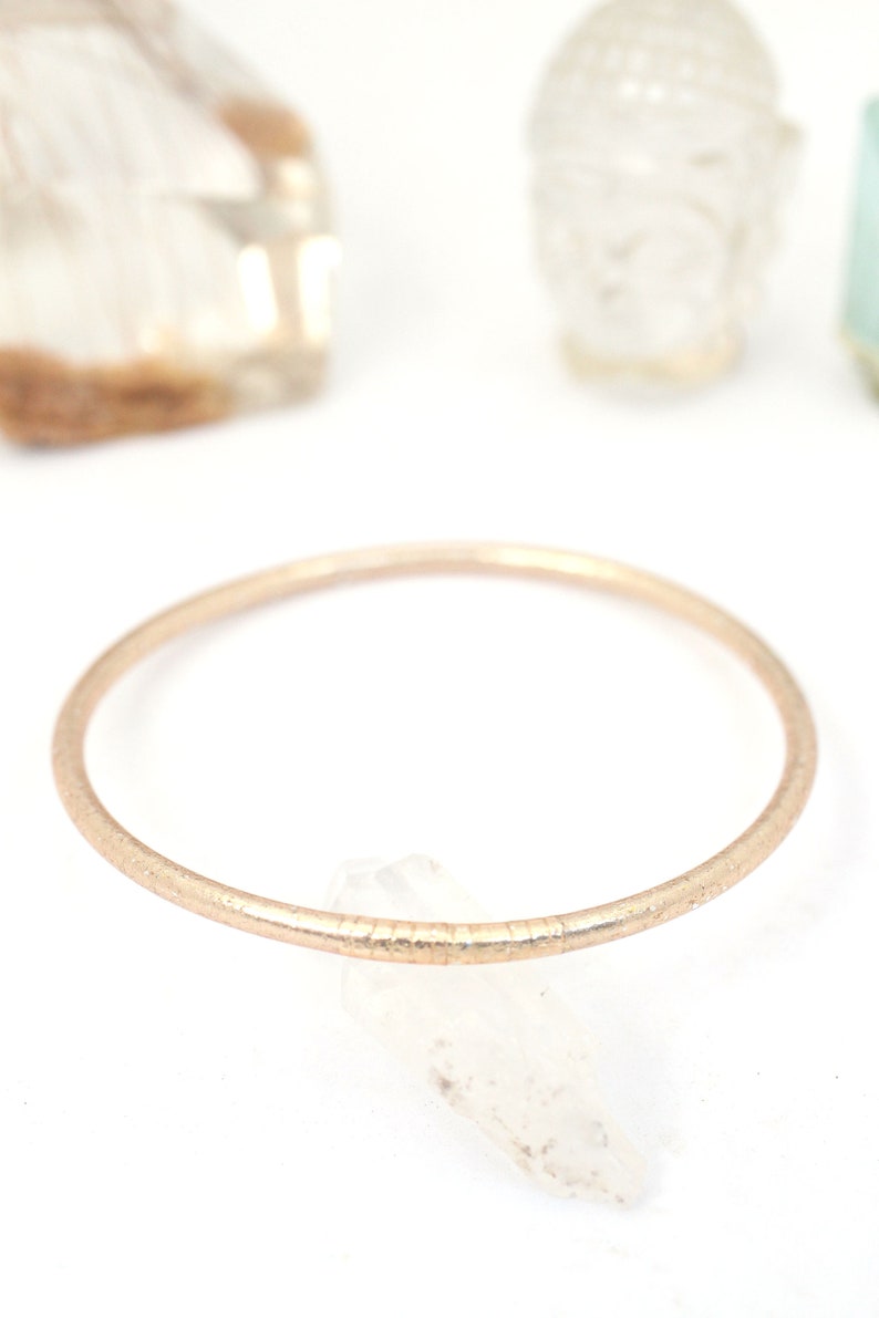 May include: A simple gold-toned bangle bracelet with a textured finish.