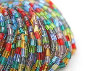 May include: A close-up of a bundle of colorful glass beads. The beads are small and rectangular, and they are arranged in a random pattern. The beads are a variety of colors, including red, orange, yellow, green, blue, and purple.