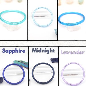 May include: A collection of six colorful, round bracelets in shades of aqua, blue jeans, true blue, sapphire, midnight, and lavender. Each bracelet is displayed against a white background with the color name above it.