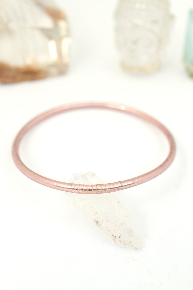 May include: A delicate rose gold bangle bracelet with a textured finish.