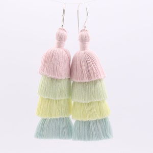 May include: A pair of layered tassel earrings in pastel pink, light green, and light blue colours. The earrings are made of cotton thread and have silver hooks.