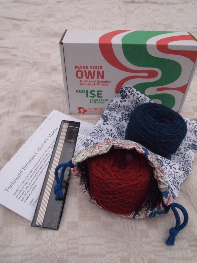 Pu&ograve; includere: Un kit per realizzare guanti tradizionali estoni in colorwork. Il kit include due gomitoli di lana, uno rosso e uno blu, un set di ferri da maglia e una borsa con coulisse con un motivo floreale. La scatola presenta il testo "Make Your Own Traditional Estonian Colorwork Mittens" e "KOO'ISE ehedad Eesti kirikindad".