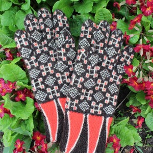 Puede incluir: Guantes de punto con un patrón geométrico en negro, blanco y coral. Los guantes tienen un puño a rayas rojas y blancas, sobre un fondo de hojas verdes y flores rojas.