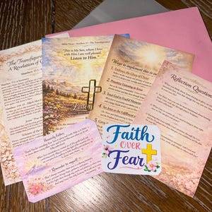 May include: A collection of printed cards and a sticker with religious themes. The cards feature text about faith, scripture, and reflection questions. The sticker reads "Faith Over Fear" with a cross and floral accents. A pink envelope is also present.
