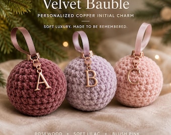 May include: Three round crochet baubles in rosewood, soft lilac, and blush pink. Each bauble features a satin ribbon loop and a copper-colored metal initial charm hanging from the top. The text reads Velvet Bauble, Personalized Copper Initial Charm, Soft Luxury. Made to be remembered. Rosewood, Soft Lilac, Blush Pink.