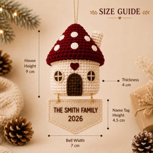 Puede incluir: Un adorno de ganchillo en forma de casa seta con techo rojo oscuro y lunares blancos, cuerpo crema, puerta marr&oacute;n y un coraz&oacute;n. Debajo cuelga una etiqueta beige con el texto THE SMITH FAMILY 2026. Dimensiones: 9 cm de altura, 4 cm de grosor, 7 cm de anchura, 4,5 cm de altura de etiqueta.