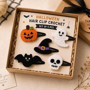 Może przedstawiać: Zestaw pięciu spinek do włosów na Halloween w kartonowym pudełku. Szydełkowe wzory obejmują pomarańczową dynię, białego ducha, czarny kapelusz czarownicy z fioletową wstążką, czarnego nietoperza oraz białą czaszkę na karcie ekspozycyjnej.