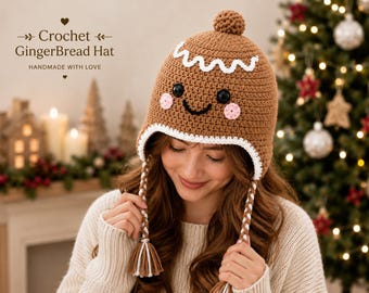 May include: A brown crochet gingerbread hat featuring a white wavy icing trim, a small pom-pom on top, and two braided earflaps with tassels. The hat has black button eyes, a black stitched smile, and pink circular cheeks. Text reads: Crochet GingerBread Hat.